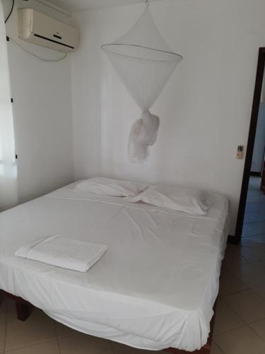 - un lit blanc dans une chambre avec un mur dans l'établissement DINO 4, à Trou aux Biches
