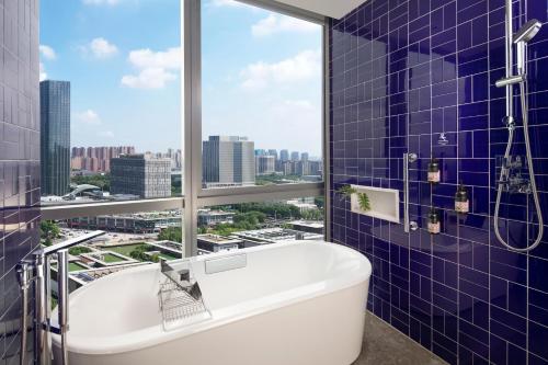 uma casa de banho com banheira e uma grande janela em M Social Hotel Suzhou em Suzhou