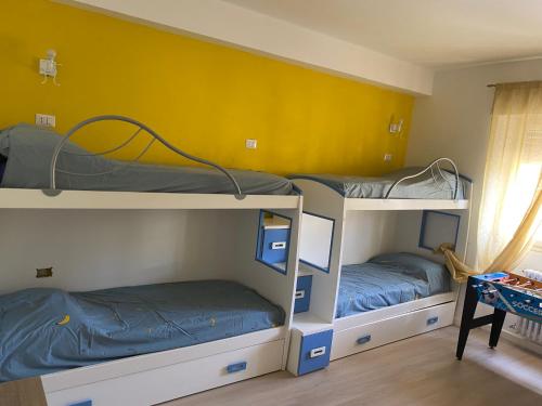 2 literas en una habitación con una pared amarilla en Amor blue -Relax and Beach, en Marina di Carrara