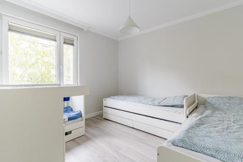 a white bedroom with a bed and a window at Black Chairs - Apartament blisko morza in Gdańsk
