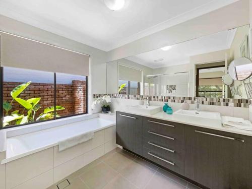 a bathroom with two sinks and a large window at Absolute Beach Front Home -Dogs, Surf, Relax, Bush in Kawana Waters