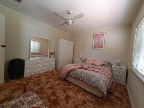 a bedroom with a bed and a ceiling fan at The House with the Purple Gate in Broken Hill