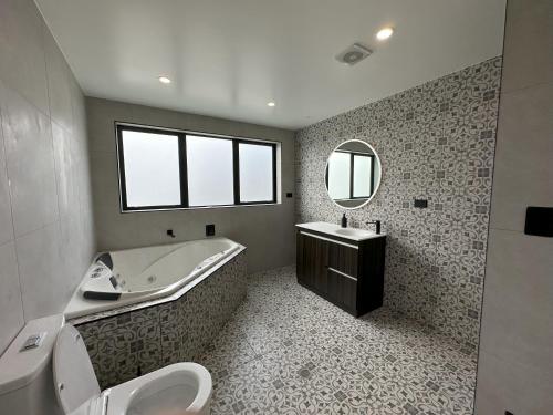 a bathroom with a tub and a sink and a toilet at Royal Residency in Auckland