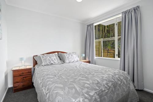 a white bedroom with a bed and a window at Takamatua Holiday Home in Takamatua Bay