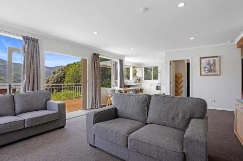 a living room with two couches and a large window at Takamatua Holiday Home in Takamatua Bay