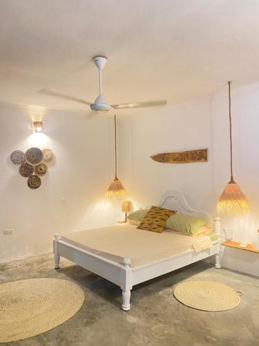 a bedroom with a bed and a ceiling fan at FURAHA BEACH ROOMS in Kendwa