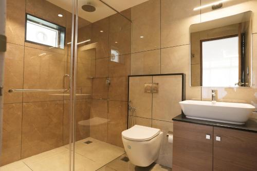 a bathroom with a shower and a toilet and a sink at Bluemist Resorts in Athirappilly