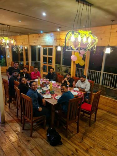 a group of people sitting around a table in a restaurant at The Mystic Pines in Nainital
