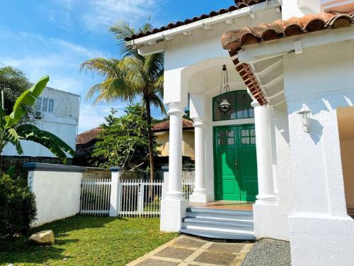 una casa bianca con una porta verde e una recinzione di DnS House a Babakan Madang