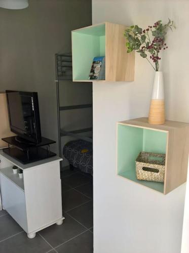 - deux photos d'un salon avec une télévision et une étagère dans l'établissement Le studio médocain, à Cussac-Fort-Medoc