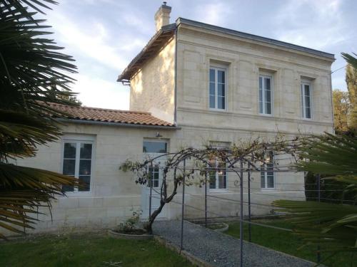 una vieja casa de piedra con un árbol delante en Le studio médocain, en Cussac-Fort-Medoc