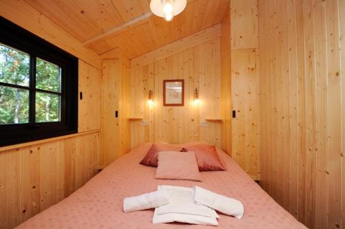 a bedroom with a bed in a wooden cabin at Camping Castels Chateau de Chanteloup in La Croix