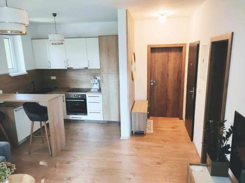 a kitchen with white cabinets and a wooden floor at Apartment Phoenix in Štôla