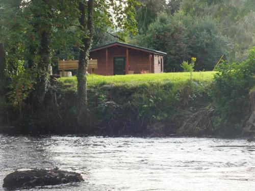 a cabin on a hill next to a river at Killarney Cabins, Stunning Timber Lodges in Killarney