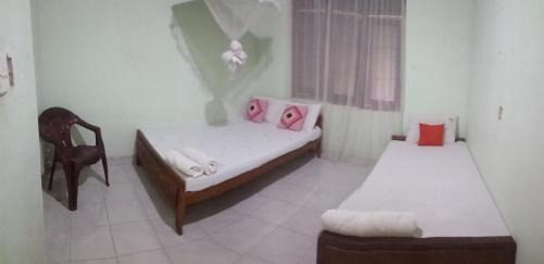 Habitación pequeña con 2 camas y silla en Oshee Home en Polonnaruwa