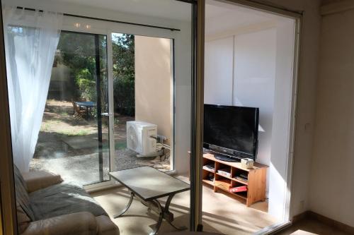 - un salon avec une télévision et une porte coulissante en verre dans l'établissement Appartements 2 chambres, grand jardin et parking, à Aix-en-Provence