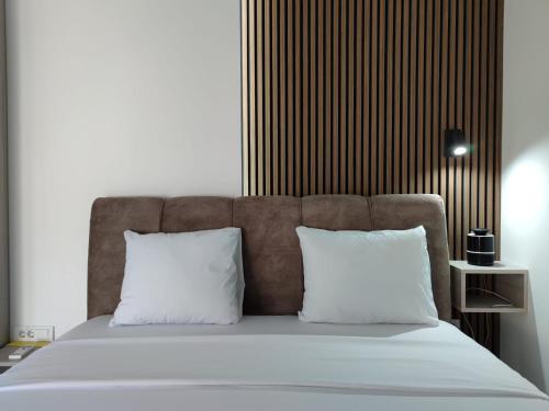 łóżko z 2 białymi poduszkami i brązowym zagłówkiem w obiekcie Nikolic Apartment 2 w mieście Leskovac