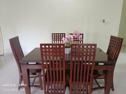 einem Holztisch mit vier Stühlen und einer Vase aus Blumen in der Unterkunft Homestay Yasmeen in Marang