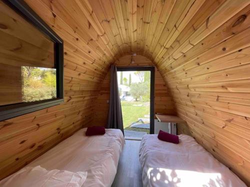 2 Betten in einem Blockhaus mit Fenster in der Unterkunft La Casa du Lez (piscine chauffée) in Montferrier-sur-Lez