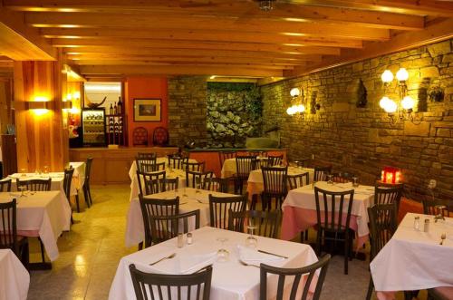 un restaurante con mesas y sillas blancas y una pared de ladrillo en HOTEL VICTORIA, en Arinsal