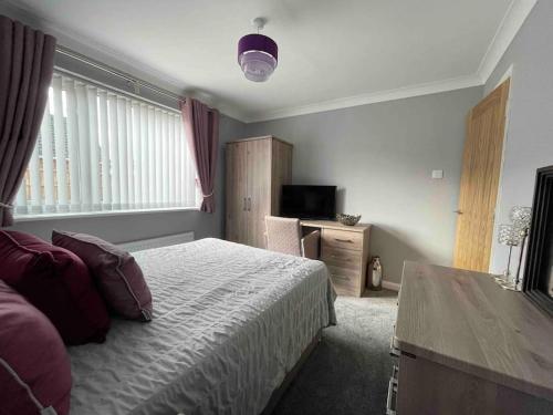 Dormitorio con cama, escritorio y TV en lodge in the heart of Bourne, en Lincolnshire