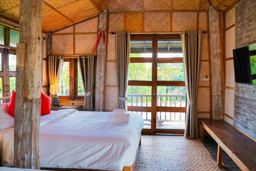 a bedroom with a bed and a large window at baanchandra in Chiang Mai