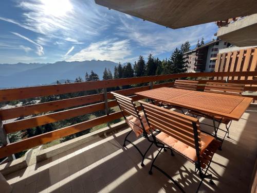 a wooden table and chairs on a balcony with a view at Eden Resort Anzère in Anzère