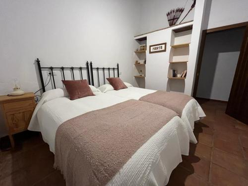 1 dormitorio con 2 camas con sábanas blancas y almohadas marrones en Casa de campo Fuencaliente, entorno natural, chimenea, piscina en Cañete la Real