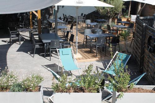 un patio al aire libre con mesas, sillas y sombrillas en Domaine de la Palme, en Lapalme