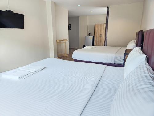 two beds in a room with a tv on the wall at Pacific Residence in Hat Yai