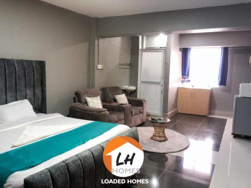 um quarto com uma cama, um sofá e uma televisão em Loaded homes em Kikuyu