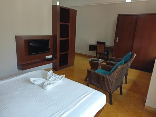 1 dormitorio con 1 cama, sillas y TV en TRANSTREE at Brookfields, en Bangalore