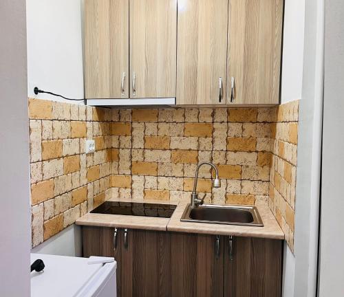 a kitchen with wooden cabinets and a sink at Hotel Sunny in Akhaltsikhe