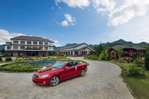 a red car parked on a driveway in front of a house at Thao Nguyen Resort Moc Chau in Mộc Châu