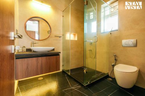 a bathroom with a sink and a toilet and a mirror at StayVista at Villa Vaari with Pvt Pool & Gazebo in Dehradun