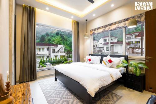 a bedroom with a large bed and a large window at StayVista at Villa Vaari with Pvt Pool & Gazebo in Dehradun