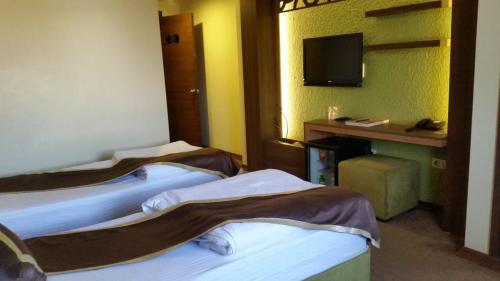 a hotel room with three beds and a television at Hotel Labella Bergama in Bergama