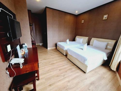 ein Hotelzimmer mit 2 Betten, einem Schreibtisch und einem TV in der Unterkunft Sinakhone Vientiane Hotel in Vientiane