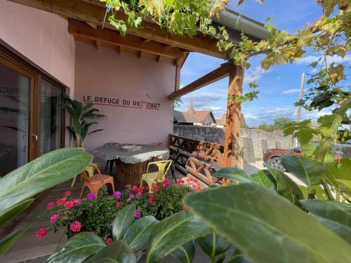 a patio with tables and flowers in front of a building at Le Refuge du Rempart in Dambach-la-Ville