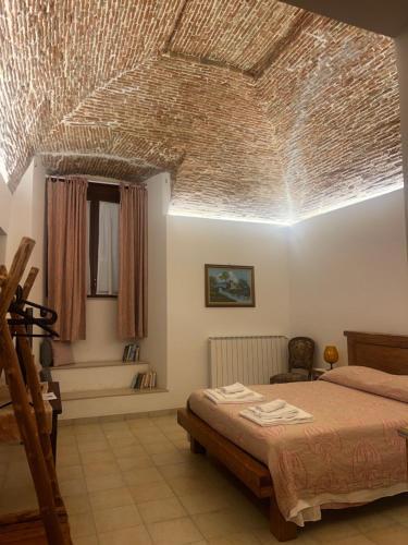 a bedroom with a bed and a ceiling made of straw at VadoLibera House in LʼAquila