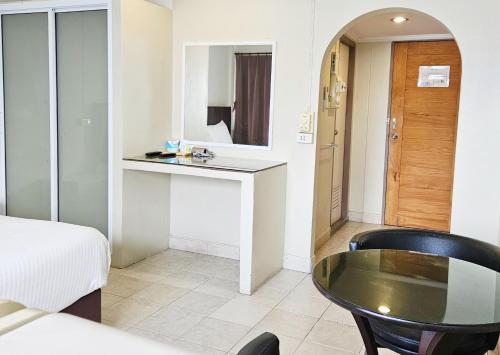 een kamer met een bed, een tafel en een spiegel bij Pacific Residence in Hat Yai