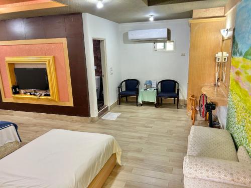 a room with a bed and chairs and a tv at TREE HOUSE in Pingtung County