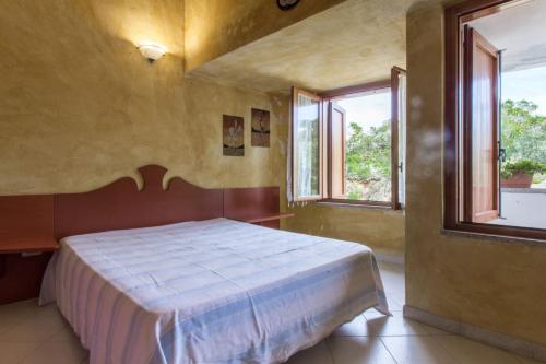 a bedroom with a bed and two windows at Capo Ceraso Family Resort in Costa Corallina