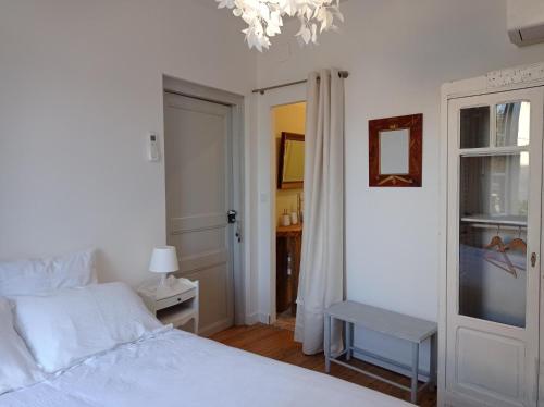 a bedroom with a white bed and a chandelier at Les Coulisses du Château in Nègrepelisse