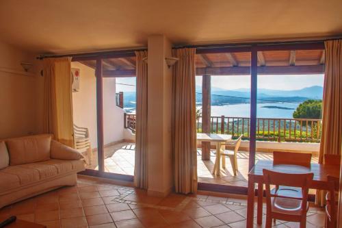 a living room with a couch and a table and a balcony at Capo Ceraso Family Resort in Costa Corallina