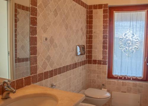 a bathroom with a sink and a toilet and a window at Capo Ceraso Family Resort in Costa Corallina