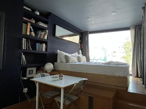 a bedroom with a bed and a table and a window at So Athens - Studios and Apartments in Athens