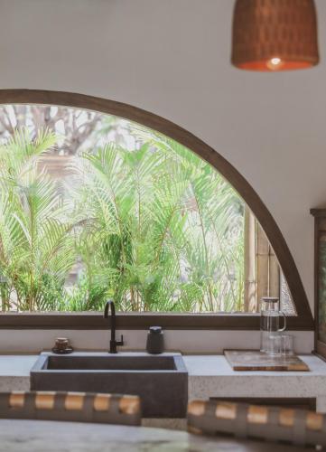 a kitchen window with a sink and palm trees outside at Kalyana Villa Gili Air in Gili Islands