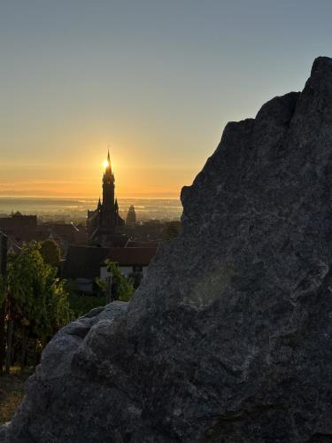 a sunset over a city with a clock tower in the background at Le Refuge du Rempart in Dambach-la-Ville