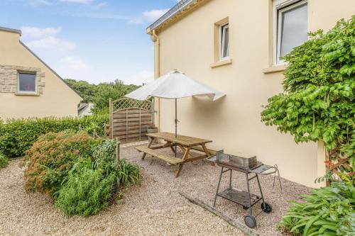a picnic table with an umbrella and a grill at Gîte des Gardiens de Phare in Lézardrieux